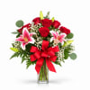 Red roses and pink lilies in a clear glass vase with a red bow