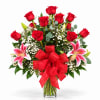 Red roses and pink lilies in a glass vase with a red bow