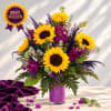 Sunflower bouquet in a purple vase with purple accent flowers