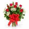 Red roses in a clear glass vase with a large red bow