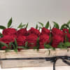 Red roses arranged in a wooden box with a black ribbon