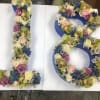 Floral arrangement shaped like the number 18 with roses and orchids