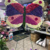 Butterfly-shaped floral display on a stand with purple and pink flowers