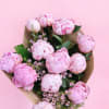 Bouquet of pink peonies with small filler flowers on brown paper