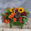 Autumn floral arrangement with sunflowers, orange roses, and red blooms in a basket