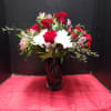 Red roses and white daisies arranged in a tall black vase