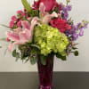 Pink lilies, roses, hydrangea, and purple flowers in a magenta vase