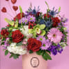 Mixed bouquet of red roses, pink daisies, and orchids in a pink hat box