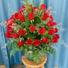 Red roses arranged in a green vase with airy filler flowers