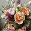 Peach and white roses with pink accents in a glass vase