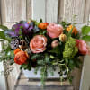 A seasonal display of kale, two toned orange roses, ranunculus and natural