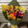 Colorful mixed bouquet wrapped in green and yellow paper with a ribbon