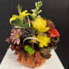 Fall floral arrangement in a pumpkin container with yellow and red blooms