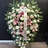 Large pink and white funeral wreath on an easel with a ribbon