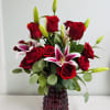 Red roses and pink lilies in a dark glass vase
