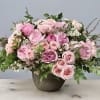 Pink roses arranged in a round vase with greenery