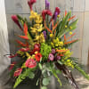 Tropical floral arrangement with orchids, roses, and bird-of-paradise in a low container