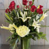 Red roses and white lilies in a tall glass vase with greenery