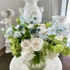 White and blue floral arrangement in a clear glass vase