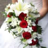 Bride holding a cascading bouquet of red roses and white lilies