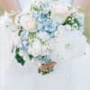 Bride holding a pastel bouquet of white, blue, and pale pink flowers