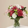 Pink roses and mixed flowers arranged in a clear glass vase