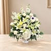 White lilies and roses arranged in a white vase with white filler flowers
