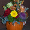Mixed bouquet arranged in a pumpkin container with bright flowers