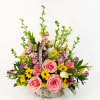 Basket arrangement with pink roses, yellow flowers, and tall pink blooms