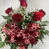 Red roses with baby's breath and a large red patterned ribbon in a glass vase