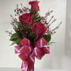 Pink roses in a clear vase with a large plaid ribbon bow