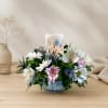 Mixed white and pink flowers arranged around a candle in a blue bowl