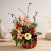Mixed floral arrangement in a red vase with pink and yellow blooms