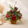 Red rose arrangement in a brown pot with berries and wheat stems