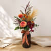 Mixed autumn bouquet in a dark glass vase with a plaid ribbon