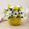 Yellow smiley-face vase filled with white and yellow daisies