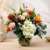 Mixed bouquet of roses, hydrangeas, and daisies in a glass vase
