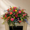 Large colorful floral arrangement with roses and mixed blooms on a mantel