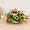 Fall floral arrangement with pumpkins in a white vase