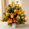 Yellow roses and orange lilies in a white vase with an orange ribbon