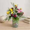 Mixed bouquet of yellow, pink, and burgundy flowers in a decorative vase