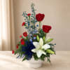 Red roses and white lilies in a white vase with a blue ribbon