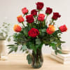 Red and orange roses arranged in a clear glass vase