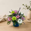 Pink and white daisies in a blue pot with green accents