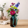 Colorful mixed bouquet in a dark glass vase with a teal ribbon