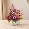 Pink and purple flower arrangement in a white mug vase