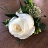 White rose boutonniere with green foliage and small filler flowers