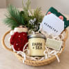 Holiday gift basket with a candle, mittens, and a small evergreen bundle