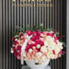 Large pink and white rose arrangement in a white vase