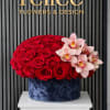 Red roses and pale pink orchids arranged in a blue velvet box